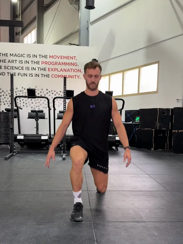 Coach Tom at the bottom of a lunge from the front, back knee down by the floor and front knee in line with his foot